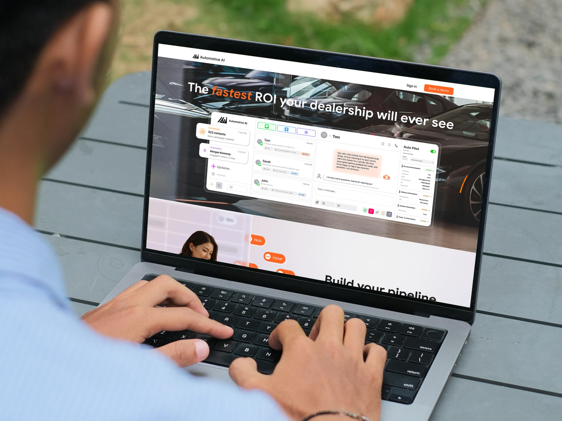 A man typing at a laptop outdoors, the Automotive AI homepage on screen with the product's inbox open over a showroom