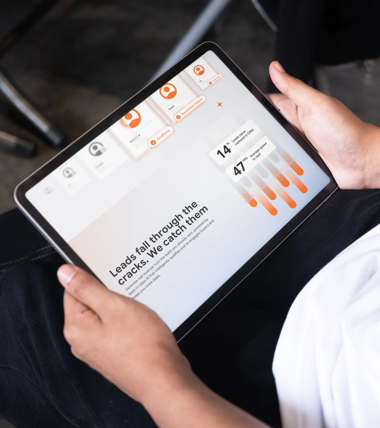 A tablet held on a lap in two hands showing the Automotive AI site, the headline Leads fall through the cracks. We catch them beside the figures 14% and 47 hrs
