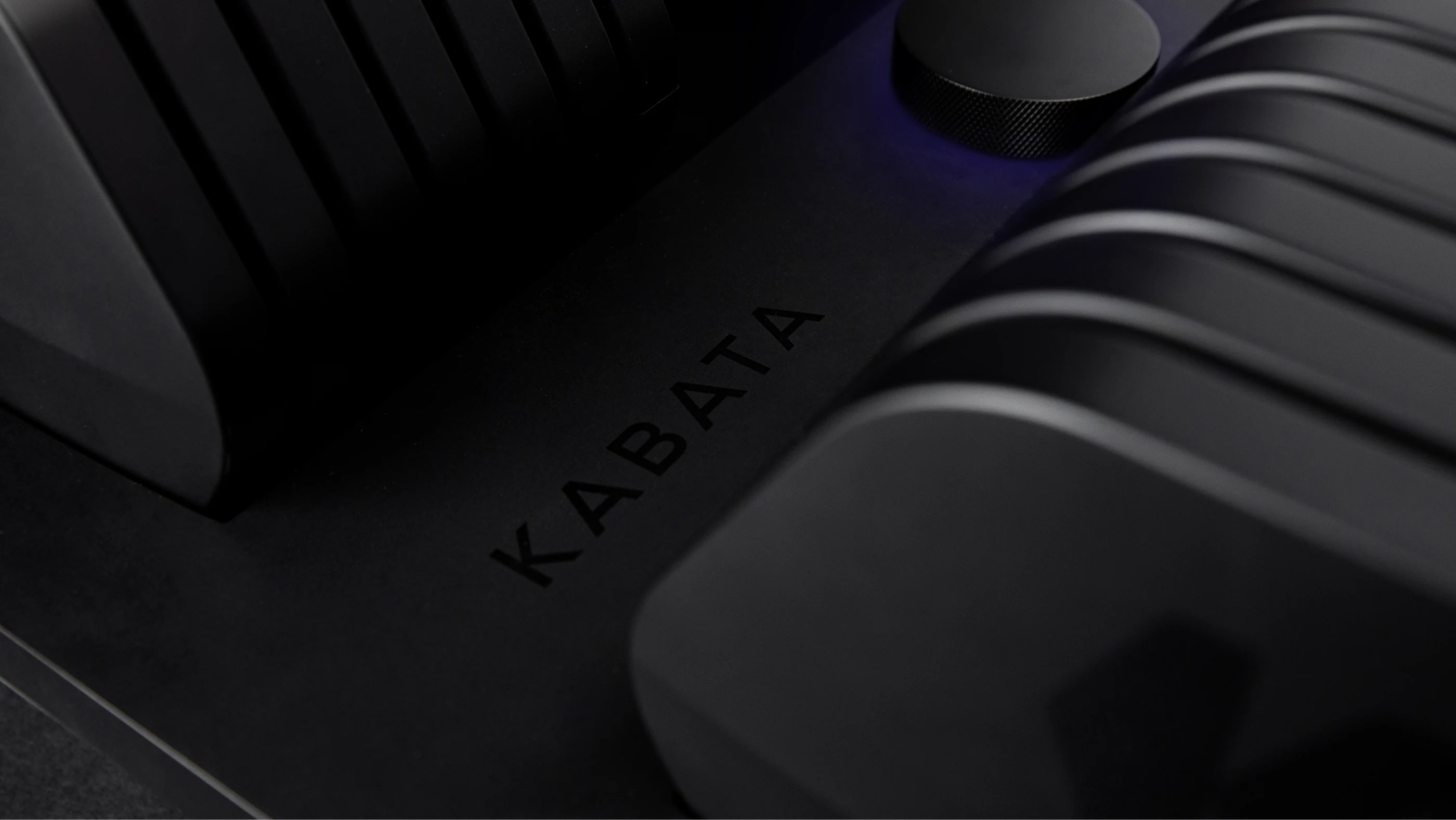 Close-up of a Kabata dumbbell, the KABATA name embossed along the black tray beside the adjustment dial