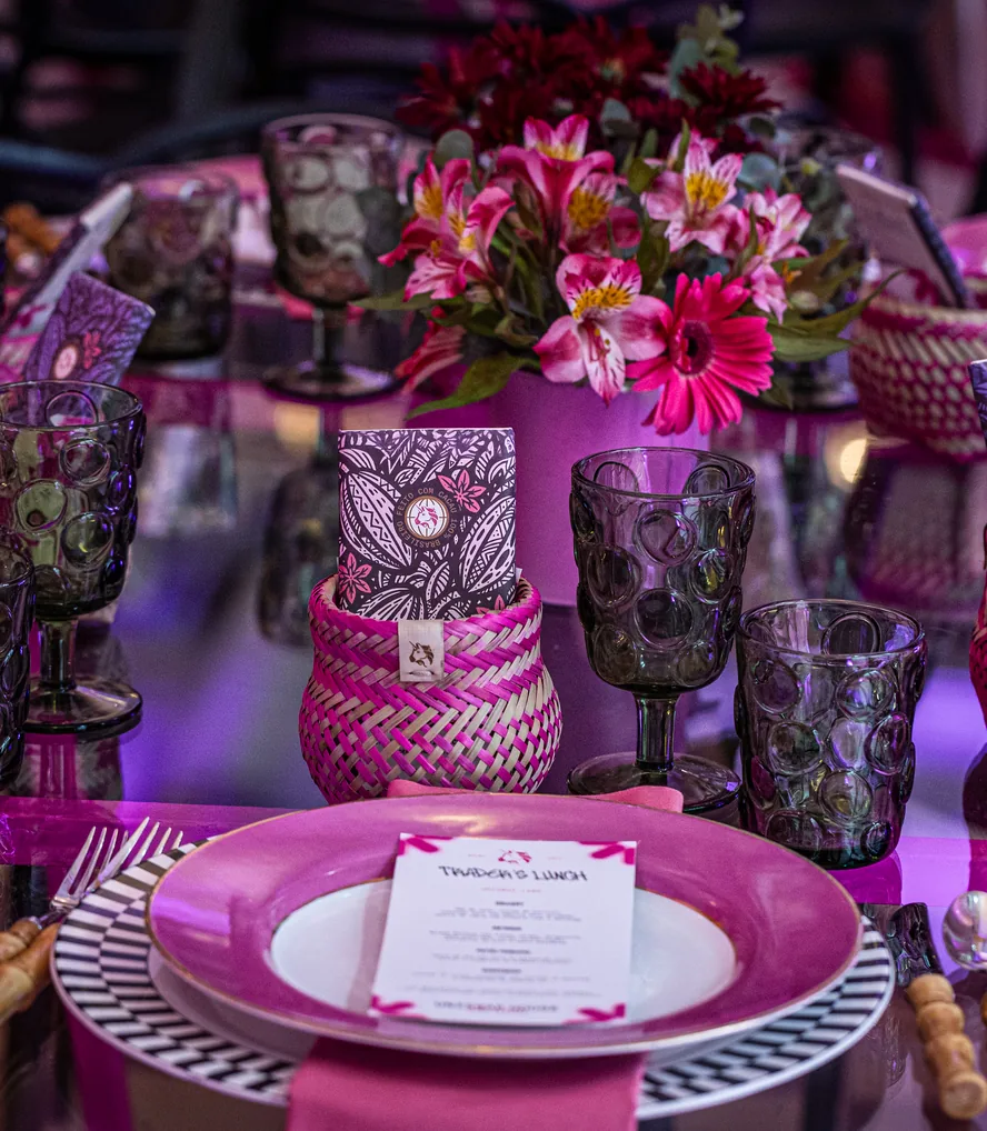 A Sao Paulo place setting, patterned glassware and woven holders under flowers, a printed menu card beside the plate