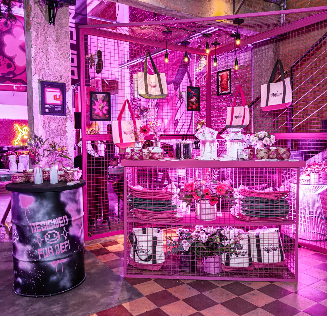 The Sao Paulo pop-up shop, totes and framed prints hung on pink mesh walls under magenta light